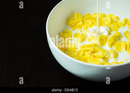 Cornflakes nella ciotola sulla tavola nera con latte di mattina Foto Stock