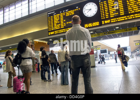 Persone che guardano gli arrivi e le partenze board presso la stazione ferroviaria di Firenze. Foto Stock