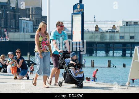 Aberystwyth, UK. 26 Ago, 2013. Una giovane famiglia passeggiando lungo la promenade, godersi il caldo clima soleggiato su agosto lunedì festivo a Aberystwyth, sulla West Wales coast. Credito: keith morris/Alamy Live News Foto Stock