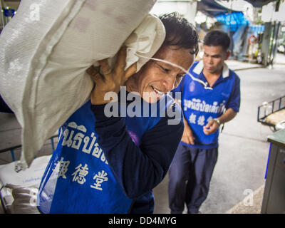 Bangkok, Tailandia. 26 Ago, 2013. Un volontario svolge il riso donato ad un magazzino a Poh Teck Tung Foundation in Bangkok. Il riso è stata donata come un merito rendendo per fame Ghost mese. Poh Teck Tung opera negli ospedali e nelle scuole e fornisce assistenza ai poveri in Thailandia. Il settimo mese lunare (Agosto - Settembre 2013) è quando la comunità cinese crede che hell's gate viene aperto per consentire spiriti di muoversi liberamente nel mondo umano per un mese. Foto Stock