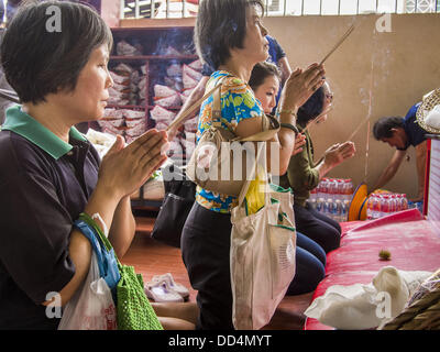 Bangkok, Tailandia. 26 Ago, 2013. Persone che pregano dopo la donazione di cibo per le Poh Teck Tung Foundation per fame Ghost mese in Bangkok. Poh Teck Tung opera negli ospedali e nelle scuole e fornisce assistenza ai poveri in Thailandia. Il settimo mese lunare (Agosto - Settembre 2013) è quando la comunità cinese crede che hell's gate viene aperto per consentire spiriti di muoversi liberamente nel mondo umano per un mese. Molte case e templi terrà cerimonie di preghiera per tutto il mese-lungo la Fame Festival fantasma (Phor Thor) per placare gli spiriti. Foto Stock