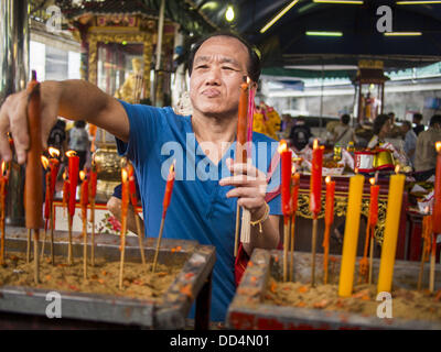 Bangkok, Tailandia. 26 Ago, 2013. Un uomo le luci e le candele per pregare presso le Poh Teck Tung Foundation per fame Ghost mese in Bangkok. Poh Teck Tung opera negli ospedali e nelle scuole e fornisce assistenza ai poveri in Thailandia. Il settimo mese lunare (Agosto - Settembre 2013) è quando la comunità cinese crede che hell's gate viene aperto per consentire spiriti di muoversi liberamente nel mondo umano per un mese. Molte case e templi terrà cerimonie di preghiera per tutto il mese-lungo la Fame Festival fantasma (Phor Thor) per placare gli spiriti. Foto Stock