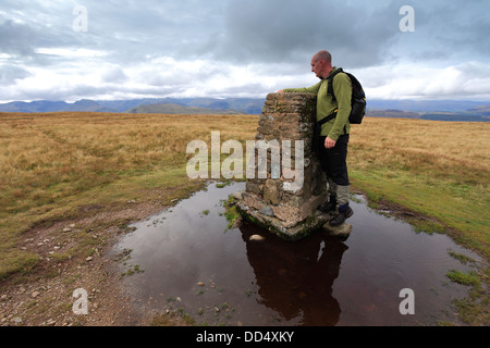 Walker, l'ordinanza sondaggio punto Trig al vertice della collina Loadpot cadde, Parco Nazionale del Distretto dei Laghi, Cumbria County, Inghilterra Foto Stock