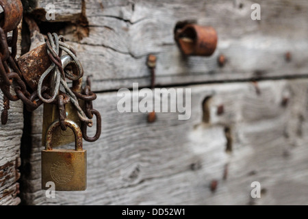 Vecchia porta di legno chiusa da una catena arrugginita e un vecchio lucchetto Foto Stock