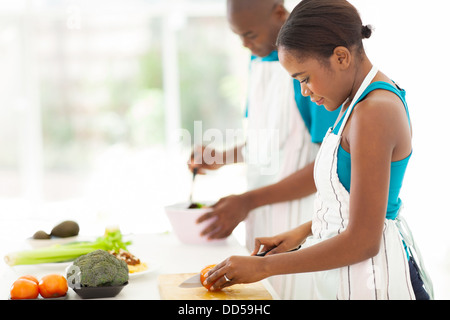 Bella giovane donna africana tritare il pomodoro in cucina Foto Stock