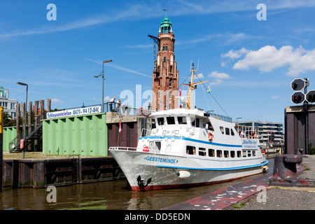 Imbarcazione turistica passando Neuer Hafen nave bloccare a Bremerhaven, Simon-Löschen-Turm faro in background Foto Stock