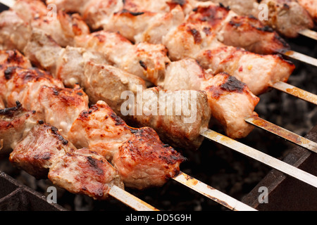 Shish Kebab in processo di cottura sul fuoco aperto all'aperto (shish kebab, spiedini). Foto Stock