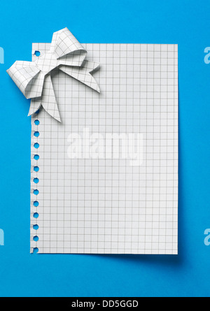Blank gift tag legato con un inchino al di fuori della carta su uno sfondo blu Foto Stock
