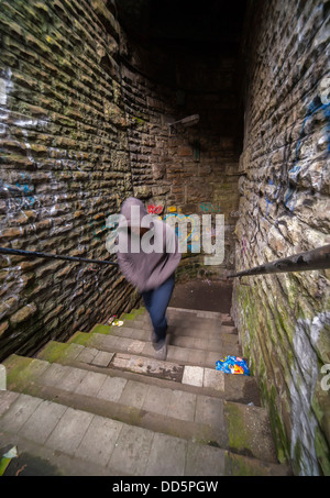 Movimento immagine sfocata di un sospetto cercando carattere emergente da un vicoletto oscurato Foto Stock