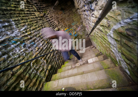 Movimento immagine sfocata di un sospetto cercando carattere emergente da un vicoletto oscurato Foto Stock