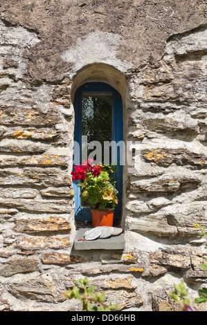 Verticale fino in prossimità di una piccola finestra ad arco in un vecchio cottage in pietra. Foto Stock