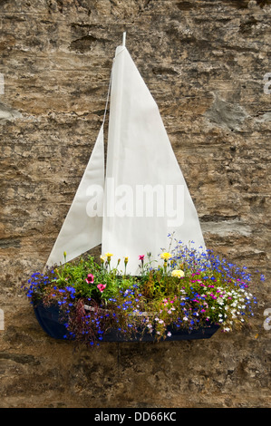Verticale fino in prossimità di un insolito barca pendenti a forma di cesto con un sacco di fiori luminosi. Foto Stock