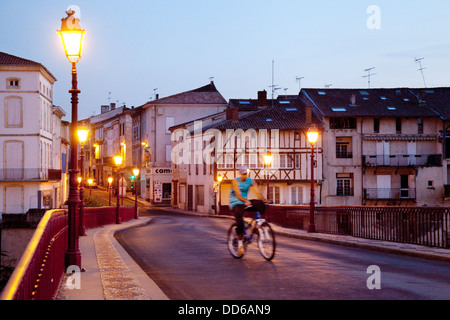 Un uomo in bicicletta di notte nella cittadina francese di Villeneuve sur Lot, Lot et Garonne, Francia Europa Foto Stock