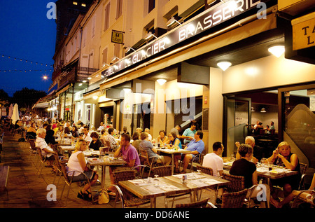 Persone mangiare all'aperto presso i ristoranti di strada di sera, la città di Villeneuve sur Lot, Lot et Garonne, Francia Europa Foto Stock