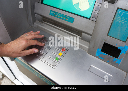 Una donna inserendo il suo numero PIN presso una banca bancomat. Foto Stock