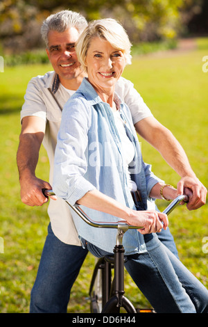 Sorridente coppia senior su una bicicletta all'aperto Foto Stock