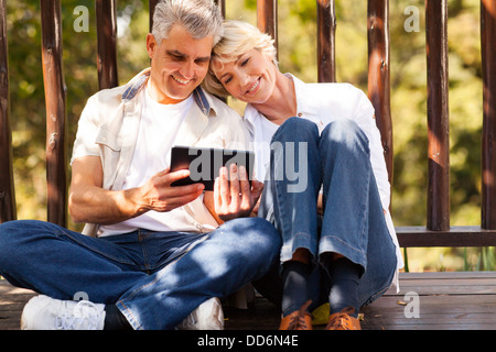 Allegro coppia senior utilizzando computer tablet all'aperto Foto Stock