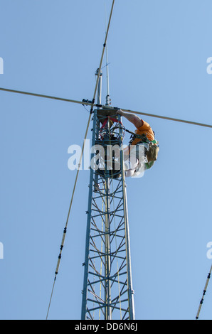 L uomo nel cablaggio di sicurezza installando un dilettante della torre radio e antenna. Foto Stock