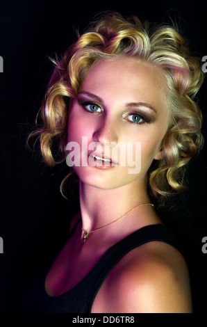 Un modello di bellezza pone ferocemente nel drammatico studio illuminazione, con Marilyn Monroe che ha ispirato i capelli Foto Stock