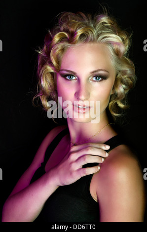 Un modello di bellezza pone ferocemente nel drammatico studio illuminazione, con Marilyn Monroe che ha ispirato i capelli Foto Stock