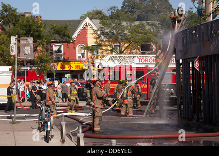 Un vigile del fuoco douses la periferica in legno di un edificio abbandonato che era sul fuoco in Kensington market, Toronto, Ontario, Canada Foto Stock