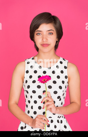 Romantico Ritratto di giovane donna multirazziale tenendo un pink gerbera daisy Foto Stock