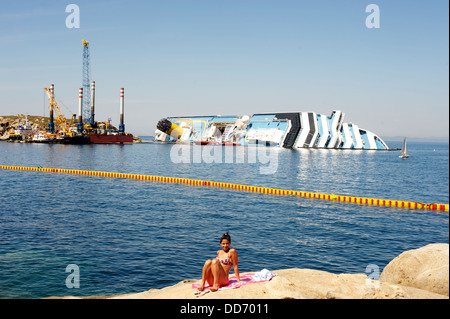 Un turista a prendere il sole di fronte al relitto della Costa Concordia cruise Foto Stock