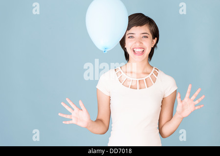 Giovane e bella donna multirazziale celebrando e giocare con palloncino blu Foto Stock