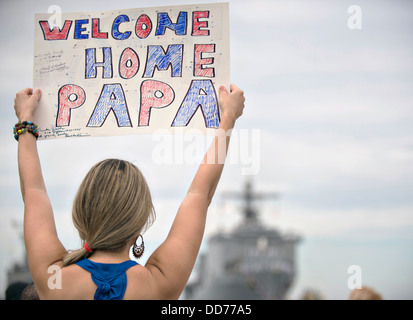 Una giovane donna contiene un segno casa accogliente a suo padre come il Navy US amphibious dock landing ship USS Pearl Harbor torna a casa dopo quattro mesi di deployment Agosto 26, 2013 a San Diego, CA. Foto Stock