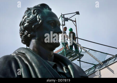 Due lavoratori di sostare dietro una statua di Johann Wolfgang von Goethe su Goetheplatz square a Francoforte sul Meno, Germanyx, 28 agosto 2013. Essi lavorano su un ponteggio in un cantiere e trasportare materiale da costruzione fino al palazzo. Foto: FRANK RUMPENHORST Foto Stock