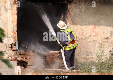 Il vigile del fuoco in forma con il tubo flessibile di spegnere un incendio Foto Stock