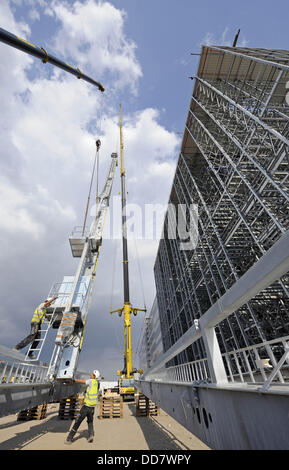 Due dipendenti di guardia a gru inserimento di una parte di un dispositivo per prelevare le cose dai ripiani in un pallet rack alto sul sito della costruzione del libro grossista Koch, Neff & Volckmar GmbH (KNV/Stoccarda) a Erfurt, Germania, 28 agosto 2013. Dal magazzino, un quarto dei libri per la lingua tedesca del mercato del libro sono pianificate per essere consegnati a partire dal 2015. Foto: Jens-ULRICH KOCH Foto Stock