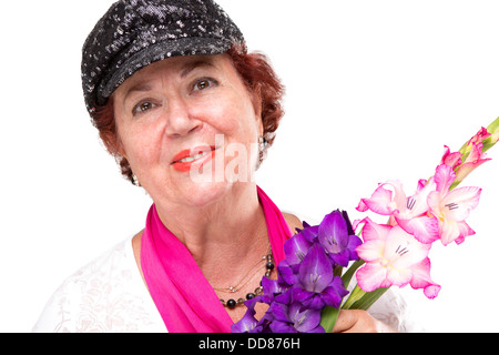 Senior signora sorridente alla telecamera felicemente con il suo nero elegante cappello e azienda gladiolus fiori. Isolato su bianco. Foto Stock