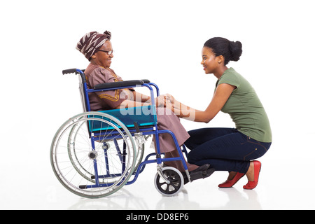 Amorevole figlia africana parla di disabili madre senior su sfondo bianco Foto Stock