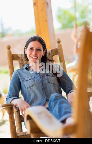 La donna caucasica rilassante in sedia a dondolo Foto Stock