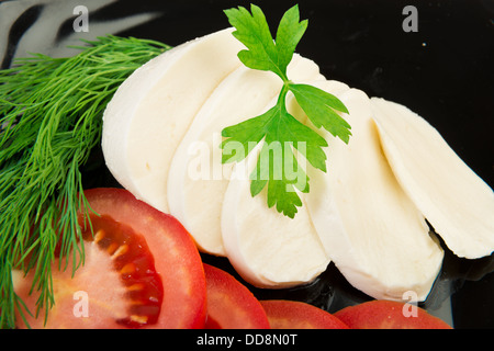 Fette di mozzarella alla piastra nera con i pomodori e le erbe Foto Stock