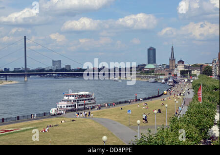 La passeggiata sul lungofiume del Reno a Dusseldorf, Renania settentrionale-Vestfalia, con Oberkassel ponte sul Reno (l-r), Sky Office tower, ERGO ufficio torre, Lambertus chiesa e Schlossturm (torre di castello) in background. Una nave passeggeri della Köln-Düsseldorfer Rheinschifffahrt può essere visto nella parte anteriore. Immagine dal 3 agosto 2013. Foto Stock