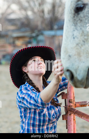 Ragazza caucasica petting cavallo in agriturismo Foto Stock