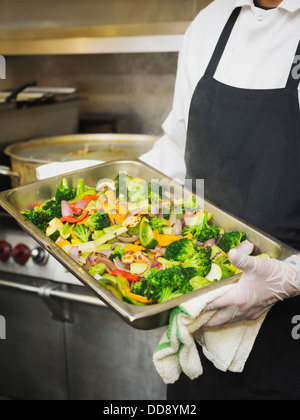 Lo chef ispanica con vassoio di verdure in cucina Foto Stock