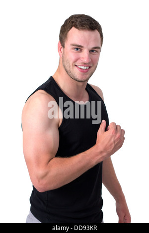 Giovane uomo attraente flettendo il suo bicipite e sorridente Foto Stock