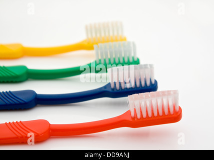 Dettaglio di una fila di diversi spazzolini da denti colorati con quella anteriore in fuoco selettivo buona per dentisti Foto Stock
