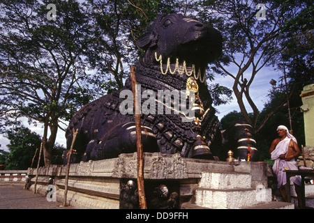 Il Nandi accovacciato scolpito da un unico pezzo di granito nero al tempio di Chamundeshwari che prende il nome da Chamundeshwari o Durga, la forma feroce di Shakti, Una divinità tutelaria tenuta in riverenza per secoli da Mysore Maharajas situato in cima alle colline di Chamundi vicino Mysore nello stato di Karnataka India del Sud Foto Stock