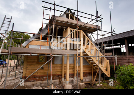 Edificio autonomo house, lavoratori erigere quercia verde incorniciato edificio, rivestimento di membrana firepoof wit listoni in legno di quercia Foto Stock