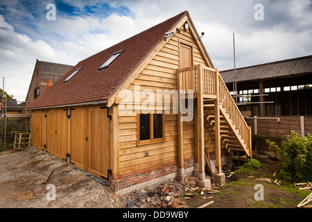 Auto costruzione di casa, quercia verde incorniciato 3 bay garage, con le scale che portano al piano superiore, e rivestito con listelli in legno di quercia Foto Stock