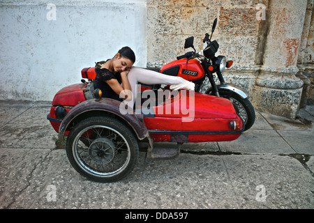 Una ballerina da Cuba National Ballet poggia su un sidecar vintage. Foto Stock