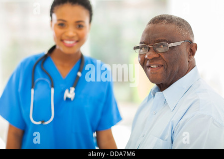 Sorridente senior African American Uomo in ufficio medici con l'infermiera sullo sfondo Foto Stock