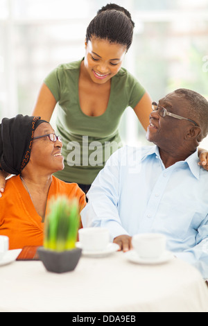 Bella ragazza africana a parlare con i genitori senior a casa Foto Stock