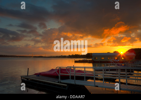 Il sole sorge su un porto turistico sul fiume San Lorenzo con il Thousand Islands Bridge in background in Alexandria Bay, NY