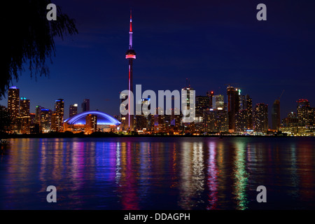 Downtown Toronto piazzali cape skyline notturno con la CN Tower e Skydome Rogers Centre si riflette nel Lago Ontario dall'Aeroporto dell'isola Foto Stock