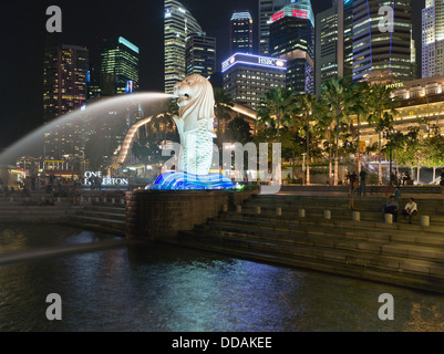 Dh Merlion Park MARINA BAY SINGAPORE statua Merlion notte tempo città delle luci skyscappers fontana Foto Stock